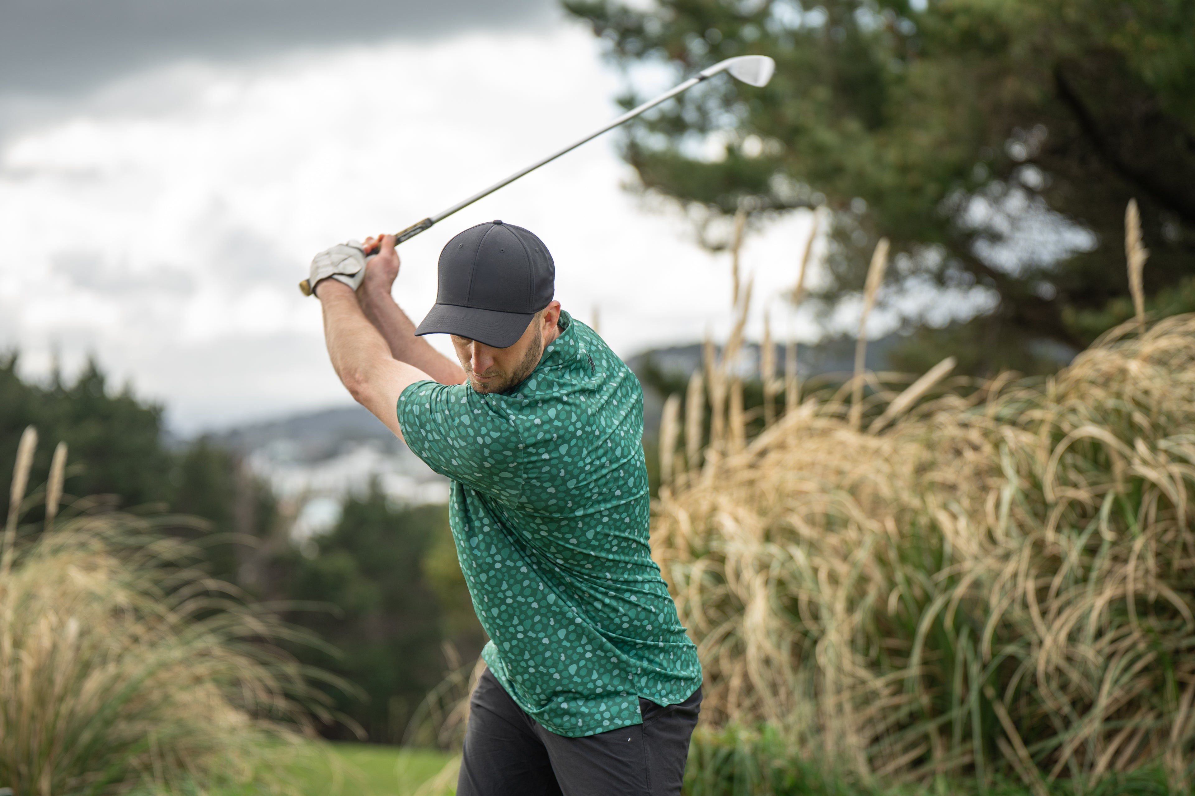 Photo of a man swinging a golf club in a Green In Reg Polo at the Mornington Golf Club