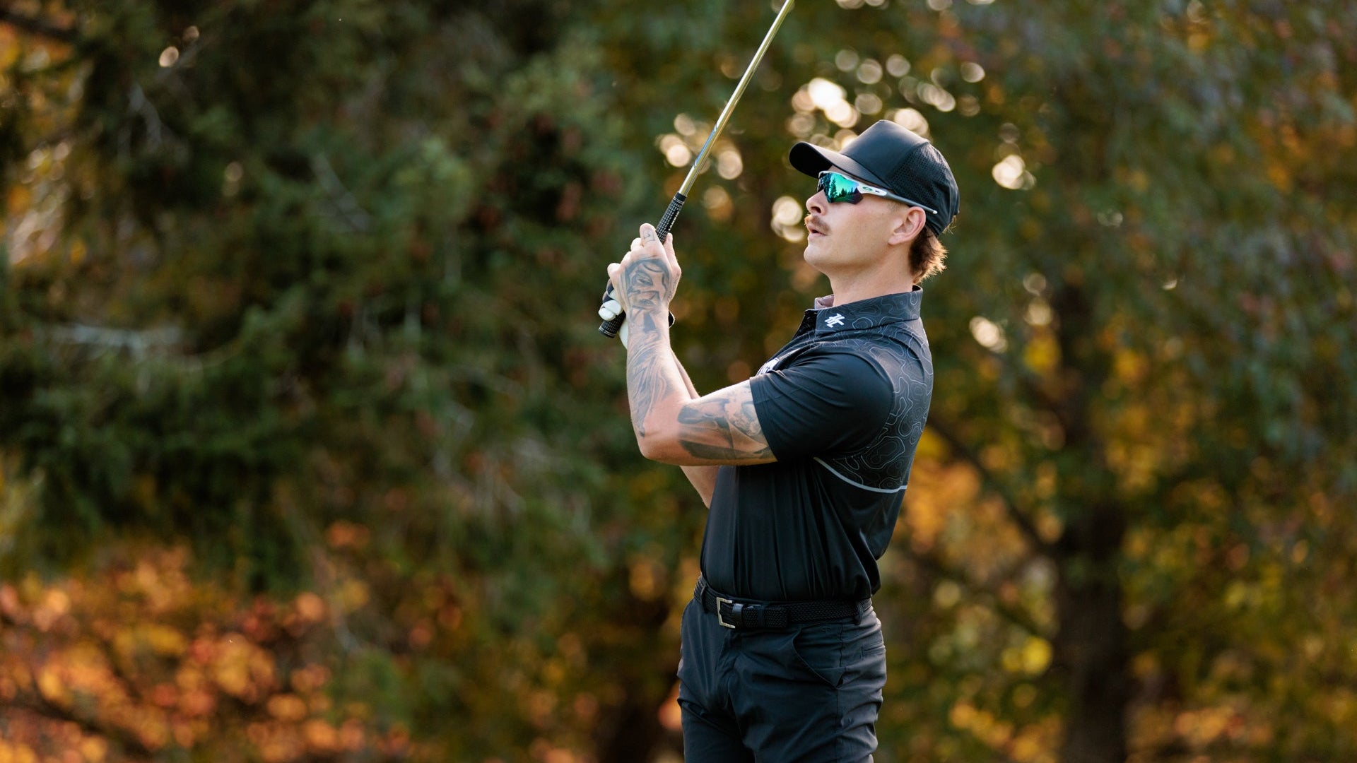 Man playing golf with trees in the background